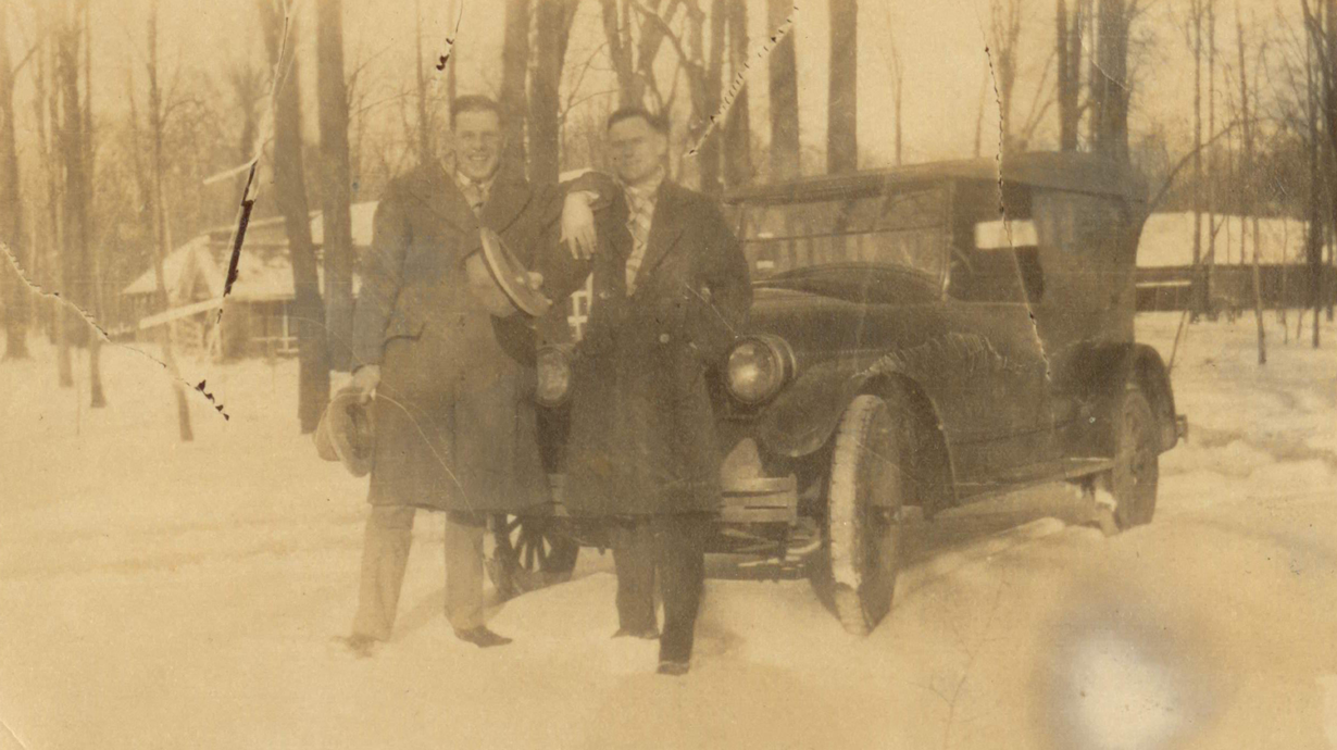 Photo restoration of picture with two men standing in front on a car from the 1940's